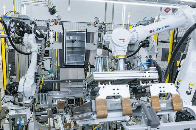 LG스마트파크 통합생산동 생산라인에 설치된 로봇팔이 20킬로그램(kg)이 넘는 커다란 냉장고 문을 가뿐히 들어 본체에 조립하는 모습/사진제공=LG전자