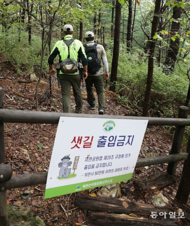 4일 오후 국립공원공단 직원들이 서울 북한산국립공원 칼바위 능선 탐방로 부근 샛길(비법정탐방로)을 순찰하고 있다. 직원들 뒤로 샛길 진입을 막아놓은 나무 울타리가 보인다. 신원건 기자 laputa@donga.com
