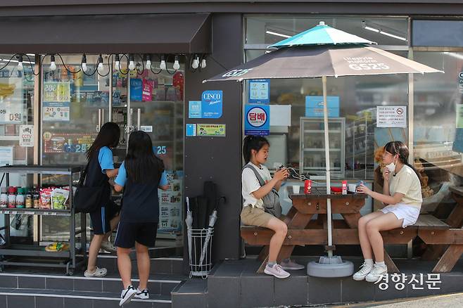 부산 동구의 한 초등학교 앞 편의점. 매일 이곳을 찾는다는 윤아(오른쪽)가 같은 구에 사는 친구 지우와 함께 파라솔 의자에서 친구와 이야기를 나누고 있다. 성동훈 기자