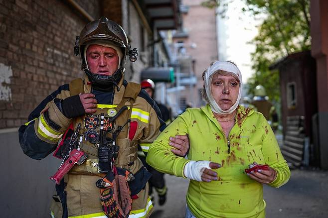 10일(현지시간) 러시아의 미사일 공격을 받은 우크라이나 수도 키이우에서 구조대원이 부상당한 시민을 구조하고 있는 모습./AFPBBNews=뉴스1