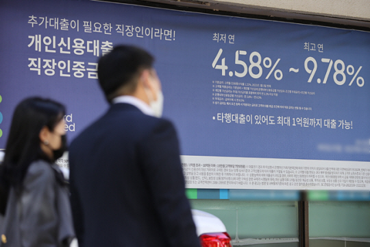 한국은행이 12일 ‘빅 스텝’을 단행해 10년 만에 기준금리가 3%까지 오른 가운데 서울 시내 한 은행에 붙은 대출 관련 현수막 앞을 시민들이 지나가고 있다. 연합뉴스