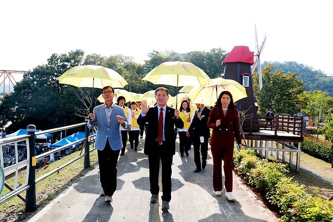 의령 리치리치페스티벌에 앞선 '미리보기' 행사에서 오태완 의령군수를 비롯한 관계자들이 해바라기우산을 쓰고 걸어가고 있다. *재판매 및 DB 금지