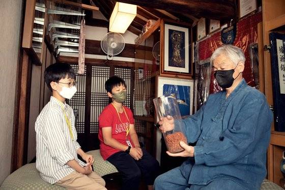 권도준·김하윤(왼쪽부터) 학생기자가 홍염에 쓰이는 재료 중 하나인 홍화를 김경열 장인과 함께 살펴봤다.