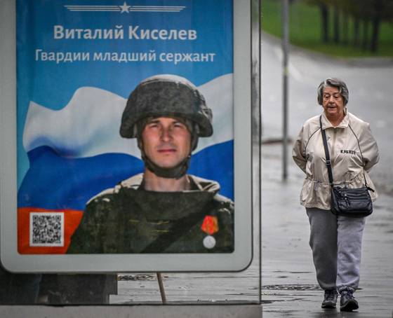 현지시간 19일 한 여성이 모스크바에서 버스 정류장 인근에 세워진 군사 홍보물 옆을 지나고 있다. 〈사진=AFP 연합뉴스〉