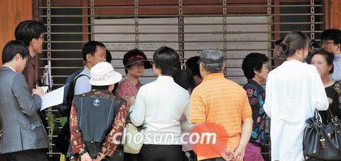 2012년 5월 금융당국의 영업 정지 조치로 셔터를 내린 채 문이 굳게 닫혀 있는 서울의 한 저축은행 지점 앞에 예금자들이 모여 있다. /조선일보DB