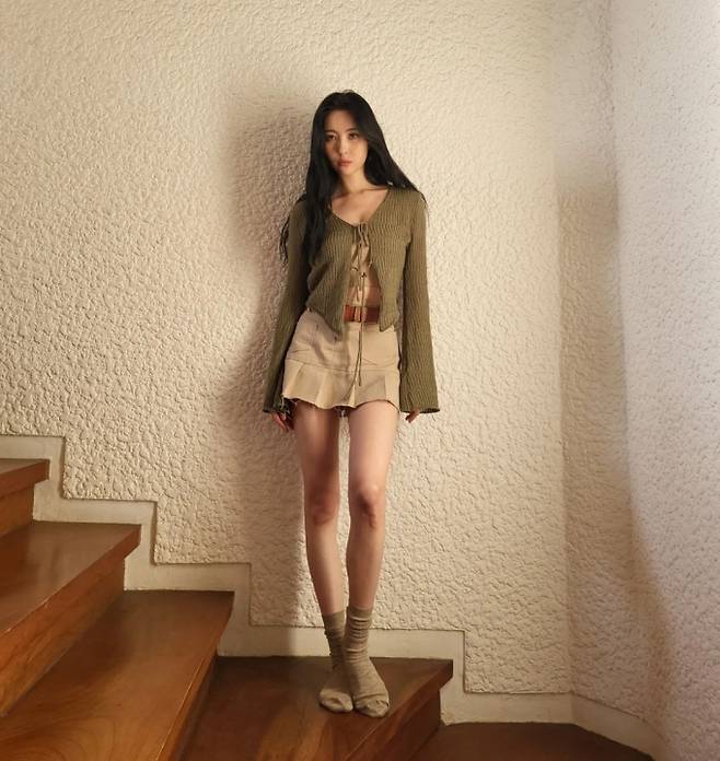 Sunmi in the public photo poses on the wooden stairs.