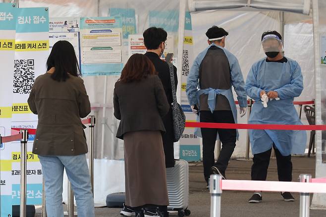 People wait in line for COVID-19 tests at a temporary COVID-19 testing station located nearby Seoul Station in Seoul, Friday. (Yonhap)