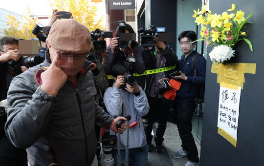 30일 이태원 압사 사고 현장에 한 시민이 추모 꽃다발을 붙이고 있다.<연합뉴스>