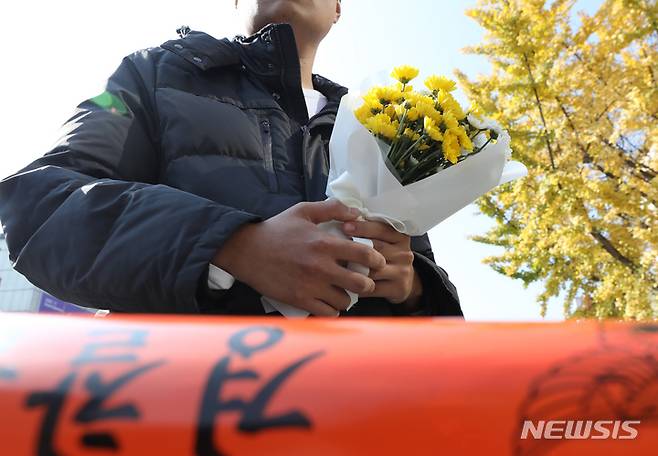 [서울=뉴시스] 김금보 기자 = 30일 오후 서울 용산구 이태원 압사 사고 현장에서 한 시민이 근조화를 들고 추모 공간 마련을 기다리고 있다.  2022.10.30. kgb@newsis.com