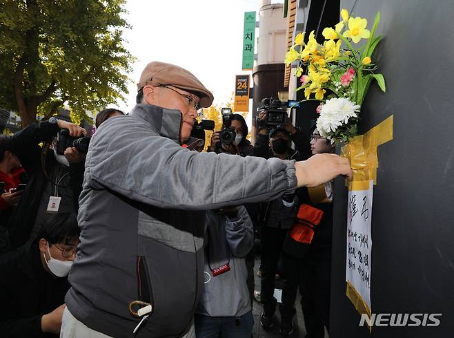 [서울=뉴시스] 김금보 기자 = 30일 오후 서울 용산구 이태원 할로윈 참사 현장 인근 건물 외벽에 한 시민이 근조화를 부착하고 애도하고 있다. 2022.10.25. kgb@newsis.com