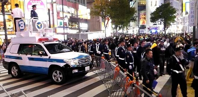 일본 경찰 기동대가 2017년 일본 핼러윈 행사의 성지인 도쿄 시부야에서 바리케이드를 설치하고 인파를 관리하고 있다. 기동대 SUV(스포츠유틸리티차량) 지붕에서는 DJ폴리스로 불리는 경찰 홍보반원들이 확성기를 이용해 보행자 통행을 유도하고 불상사를 예방한다. 유튜브 캡처