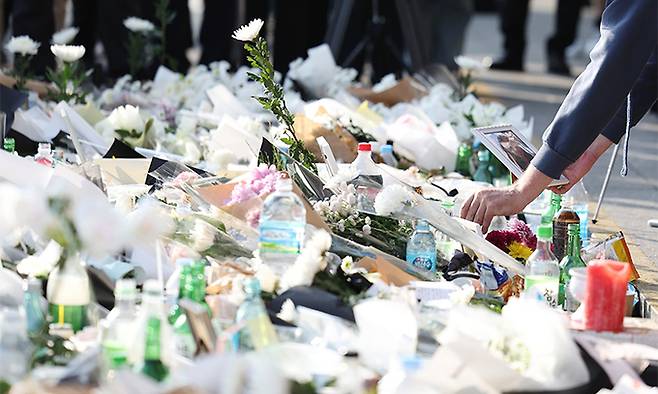 1일 서울 용산구 이태원 핼러윈데이 사고 추모공간을 찾은 외국인이 희생자로 보이는 여성의 사진을 국화꽃 사이에 내려놓고 있다. 연합뉴스