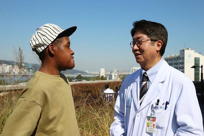 한국을 찾아 얼굴 크기만 한 종양을 성공적으로 치료받은 플란지씨(왼쪽)에게 수술을 집도한 최종우 서울아산병원 성형외과 교수가 귀국을 앞두고 덕담을 건네고 있다. /서울아산병원