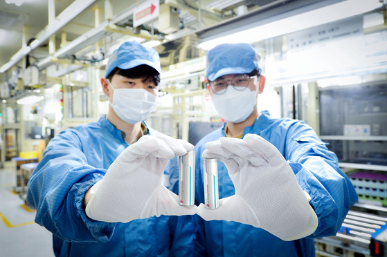 LG Energy Solution workers hold up the company's cylindrical batteries at the Ochang plant in North Chungcheong. [LG ENERGY SOLUTION]