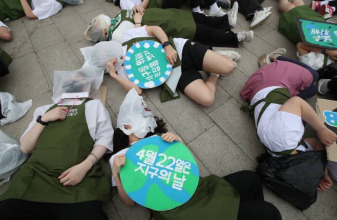 시민활동가들이 지난 4월22일 오전 서울 영등포구 여의도 한강공원에서 지구의 날을 맞아 ‘고 네이키드, 노 플라스틱’ 캠페인을 열어 일회용 플라스틱 및 비닐 쓰레기에 둘러싸인 우리들의 모습을 나타내며, 인류 생존을 위한 마지노선 1.5도를 표현하는 1분 50초 눕기 행위극을 하고 있다. 백소아 기자 thanks@hani.co.kr