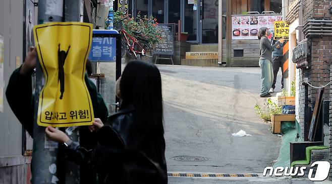 10일 서울 마포구 홍익대 정문 인근 골목에서 시민활동가들이 이제석 광고연구소가 제작한 압사 사고 위험구간 표지판을 시범 부착하고 있다. 2022.11.10/뉴스1 ⓒ News1 장수영 기자