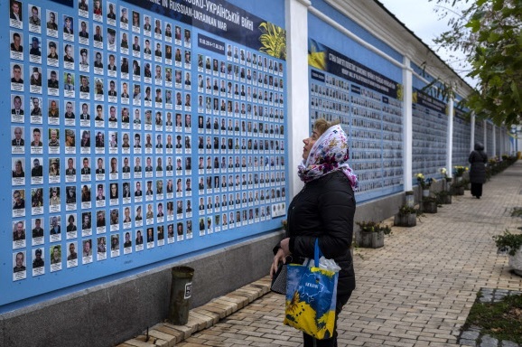 지난 7일(현지시간) 우크라이나 키이우 시내에서 한 시민이 러시아와의 전쟁으로 희생된 우크라이나 군인들 얼굴 사진이 들어간 ‘추모의 벽’을 바라보고 있다.   키이우=AP연합뉴스