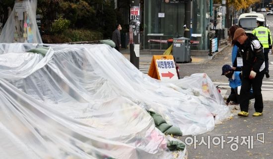 13일 서울 용산구 이태원역 1번 출구 인근에 시민들이 두고 간 국화꽃과 추모 메세지가 대형 비닐로 덮여 있다./윤동주 기자 doso7@