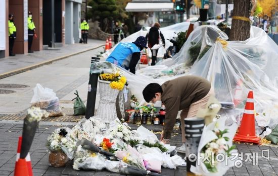 13일 서울 용산구 이태원 참사 현장 앞 인도에서 자원봉사자들과 용산구청 관계자들이 시민들이 두고 간 국화꽃과 추모 메세지를 정리하고 있다./윤동주 기자 doso7@