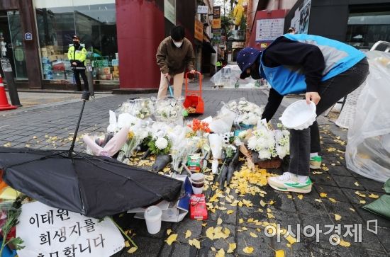 13일 서울 용산구 이태원 참사 현장 앞 인도에서 자원봉사자들과 용산구청 관계자들이 시민들이 두고 간 국화꽃과 추모 메세지를 정리하고 있다./윤동주 기자 doso7@