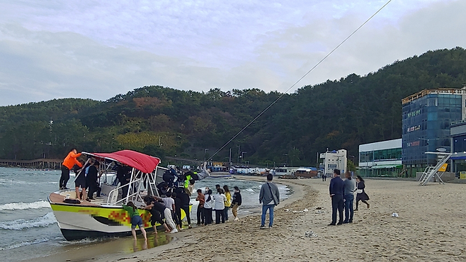 부산 기장군 한 해수욕장에서 13일 오후 3시 47분쯤  40대 여성 A씨와 A씨의 10대 아들이 패러세일링을 하던 중 강풍에 휘말려 조난되자 시민들이 구조하고 있다. 부산경찰청제공=연합뉴스.