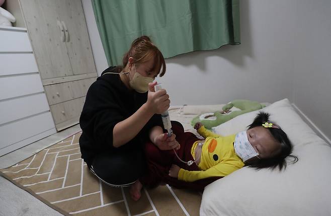 2021년 5월 뇌병변 중증장애 판정을 받은 김희진(가명) 어린이의 어머니가 위루관을 통해 약물을 주입하고 있다. 강창광 선임기자 chang@hani.co.kr