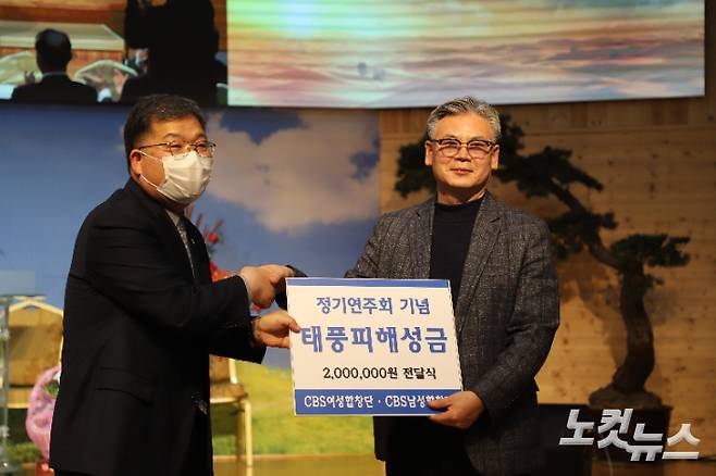 왼쪽부터 이상석 포항CBS 남성합창단 단장이 김진동 목사에게 태풍피해 복구성금을 전달하고 있다. 포항CBS