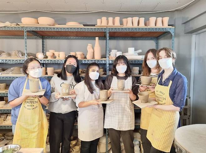 Students pose for a photo with their handmade artwork. (Anna Potter)