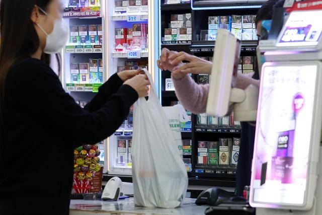 지난달 20일 오후 서울 시내 한 편의점에서 고객이 일회용 봉투에 물건을 담아 가고 있다. 뉴시스