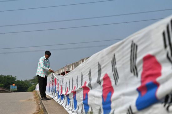 방글라데시 동부 브라흐만바리아에서 한국 축구를 응원하는 한 방글라데시 팬이 자신의 마을과 이웃 마을을 잇는 3.2㎞ 길이의 다리에 태극기를 걸고 있다. 사진=AFP 연합뉴스