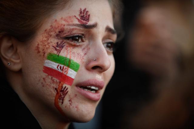 얼굴에 이란 국기와 붉은 손자국 그림을 그린 한 여성이 지난 10월 9일(현지시간) 프랑스 파리에서 열린 이란 반정부 시위대를 지지하는 시위에 나서고 있다. 파리=AFP 연합뉴스