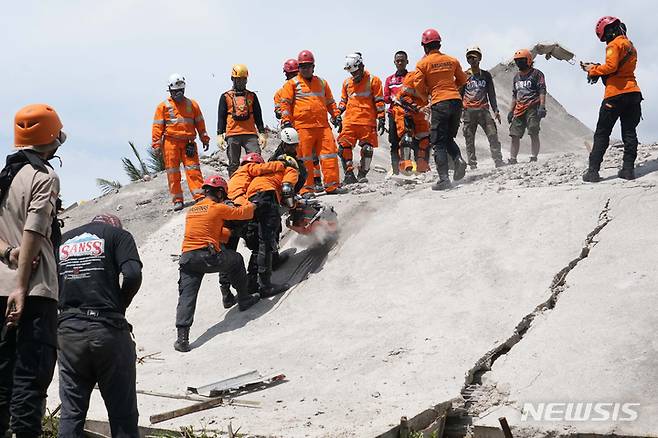 [치안주르=AP/뉴시스] 22일(현지시간) 인도네시아 서자바주 치안주르에서 구조대가 지진 희생자 시신을 수습하기 위해 전기톱으로 붕괴 건물 시멘트를 뚫고 있다. 2022.11.22.