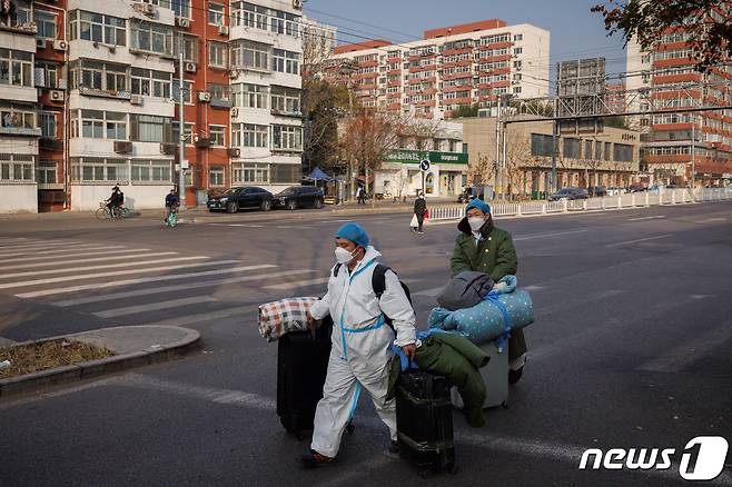 23일 중국 베이징에서 신종 코로나바이러 감염증(코로나19)가 확산함에 따라 방역 위생 관계자들이 짐을 들고 출근하고 있는 모습. 2022.11.23/뉴스1 ⓒ 로이터=뉴스1