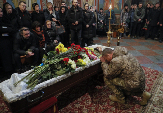 지난 2월 24일(현지시간) 러시아가 우크라이나를 침공한 후 꼭 9개월을 앞둔 23일 한 우크라이나 군인이 수도 키이우 미하일로프스키 대성당에서 열린 전우의 장례식에서 관을 붙잡고 울고 있다. EPA·연합뉴스