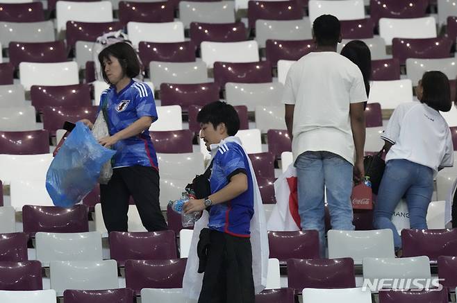 [알라이얀(카타르)=AP/뉴시스]쓰레기를 줍고 있는 일본 축구 팬