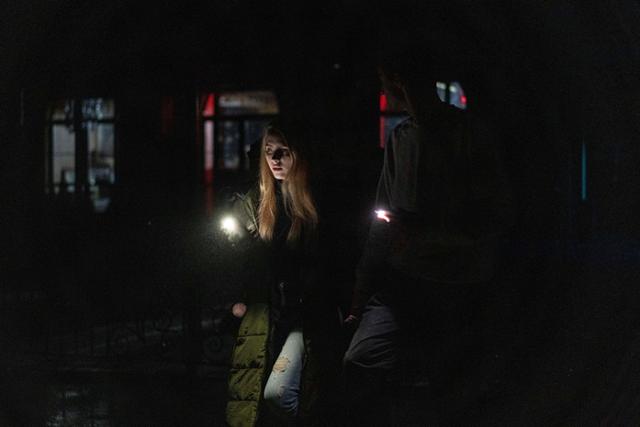 지난 24일(현지시간) 우크라이나 키이우 주민들이 전날 있었던 러시아의 무차별 공습으로 전기가 끊겨 컴컴해진 도심을 휴대전화 불빛에 의존해 걷고 있다. 키이우=AP 뉴시스