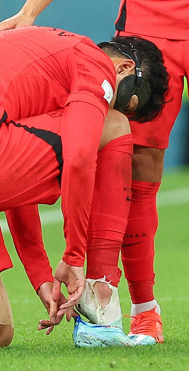 24일 오후(현지시간) 카타르 알라이얀의 에듀케이션 시티 스타디움에서 열린 2022 카타르 월드컵 조별리그 H조 1차전 대한민국과 우루과이 경기. 대한민국의 손흥민이 우루과이의 카세레스의 거친 태클에 넘어진 뒤 축구화를 신고 있다. 손흥민의 오른쪽 양말이 찢겨져 있다. 연합뉴스