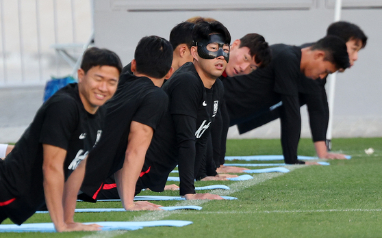Korean national team players including Son Heung-min, center, stretch during a training session at Al Egla Training Site 5 in Doha, Qatar on Friday. Korea will play their second match against Ghana on Nov. 28. [AP/YONHAP]