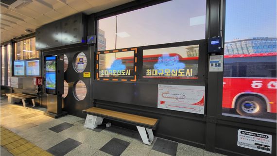 LG유플러스는 세종 스마트시티 버스정류장에 모빌리티AR 서비스를 활용한 ‘AR버스정류장’을 구축했다. 사진은 세종시 BRT 정류장에 설치된 투명 OLED에서 AR콘텐츠가 재생되고 있는 모습. LG유플러스 제공