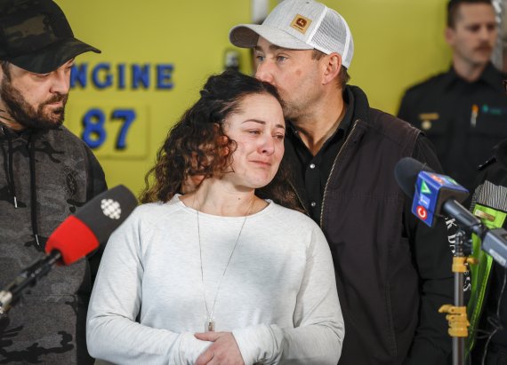 Paramedic Jayme Erickson, center, who was called to a crash last week and didn't know she was trying to save her own daughter because the injuries were too severe, is comforted by her husband Sean Erickson, as she speaks to the media in Airdrie, Alberta, Tuesday, Nov. 22, 2022. (Jeff McIntosh/The Canadian Press via AP) /뉴시스/AP /사진=뉴시스 외신화상