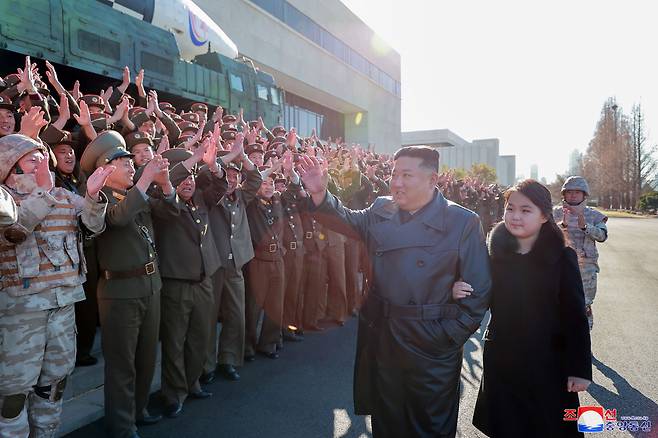 North Korean leader Kim Jong-un (L) walks hand in hand with his daughter, presumed to be his second child, Ju-ae, during a photo session with officials involved in this month's intercontinental ballistic missile launch, in this photo provided by the Korean Central News Agency on Nov. 27, 2022. (Yonhap)