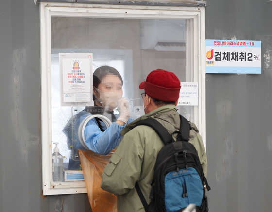 A visitor gets tested for the coronavirus at a Covid testing site near Seoul Station in central Seoul on Sunday. [YONHAP]