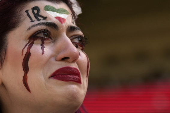 한 이란 여성이 얼굴에 이란 국기와 검은 피눈물 분장을 하고 25일(현지시각) 경기를 관람하고 있다. / 사진=AP 통신