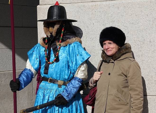 방한모인 휘양을 착용하고 문을 지키고 있는 경복궁 수문장이 외국인과 기념촬영하고 있다.