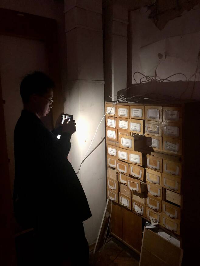 지난 10월12일 방문한 보로댠카 도서관 내부를 취재 중인 <한겨레> 기자를 키이우시 군사청 관계자(사진 제공)가 찍었다. 도서관은 전기시설도 아직 복구되지 않았다.
