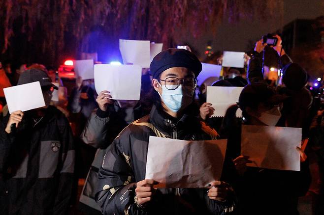 27일 중국 베이징에서 열린 우루무치 화재 희생자 추도식에서 코로나19 봉쇄 조치에 반대하는 시민들이 ‘백지 시위'를 벌이고 있다. 베이징/ 로이터 연합뉴스