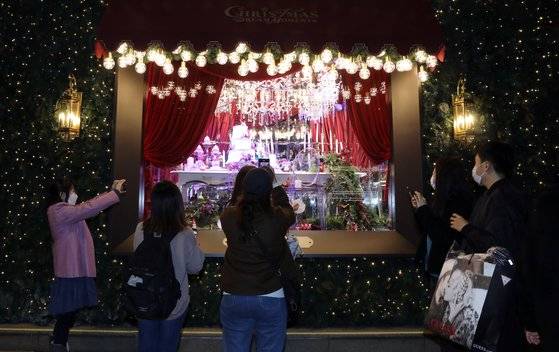 지난 20일 크리스마스 조명으로 화려하게 외벽을 꾸민 서울 중구 롯데백화점 본점 앞에서 시민들이 추억을 남기고 있다. 뉴스1