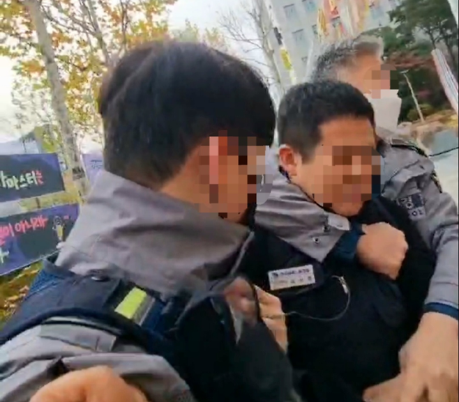 24일 오전 경찰이 김선영 금속노조 자동차판매연대지회장의 목을 팔로 감은 채 수갑을 채우려 하고 있다. 금속노조 제공