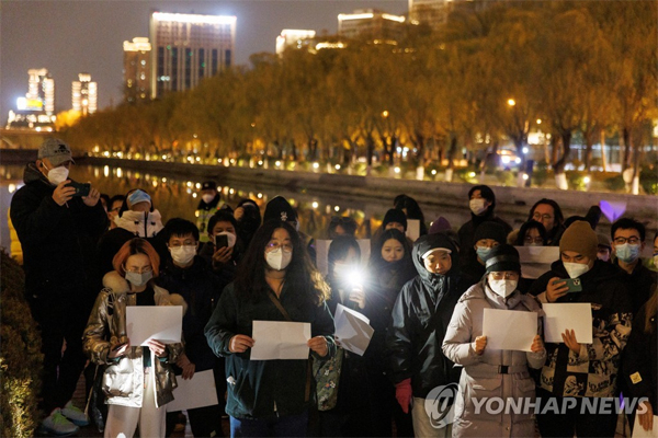 지난 27일 밤 중국 베이징에서 사람들이 백지를 든 채 우루무치 화재 희생자를 추모하고 당국의 제로 코로나 방역에 항의하는 집회를 열었다. [로이터 = 연합뉴스]