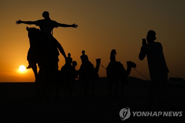 카타르 사막에서 낙타를 타고 기념 촬영을 하는 관광객들. 사진=AP·연합뉴스